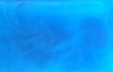 A blurred photo capturing the dispersion of dark blue watercolor drops in water, showing the spread...
