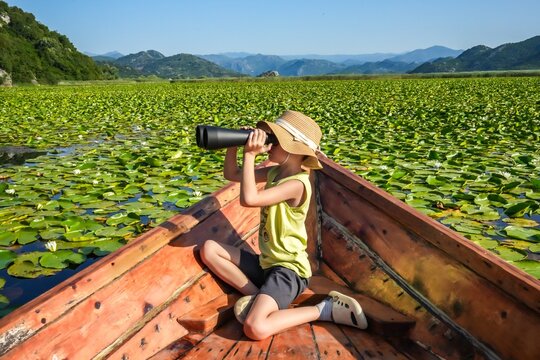 Boy in Hat Exploring Skadar Lake, Montenegro with Binoculars – Summer Travel Adventure