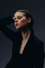 elegant woman in black outfit with contemplative expression and soft lighting against dark background, highlighting natural beauty and refined style