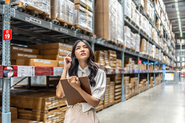 Focused on her task, Young asian woman holding clipboard meticulously updates inventory records,...