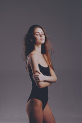 young woman in black bodysuit standing with closed eyes, natural makeup, soft lighting, relaxed...
