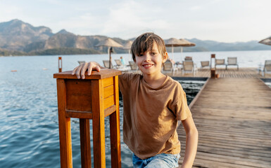 Portrait of carefree smiling Caucasian boy on sea pier during summer vacation at sea