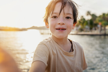 Kid boy taking selfie on seashore during summer vacation. Childhood and summer family vacation