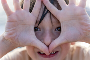 Portrait of a carefree smiling сaucasian kid boy covering his face with his palms