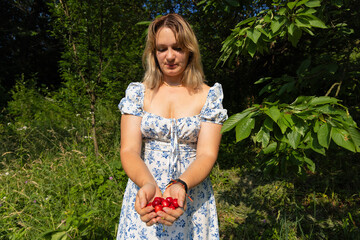 young woman in a garden holding freshli picked cherries