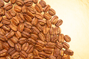 Oval pile of roasted coffee beans on a gold reflective background, revealing their warm tones and...