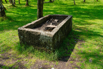 An old, rough unfinished gritstone stone trough in Bole Hill Quarry.