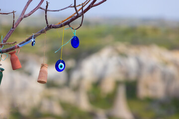 Blue Evil Eye pendants and small clay love pots in Wish tree against blurred background in Cappadocia, Turkey.