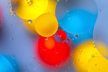 Vibrant water droplets on a colorful surface with red, yellow, blue, and green hues, creating an...