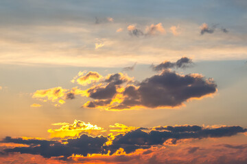 Fototapeta premium Beautiful sky at sunset with warm golden hues reflecting off scattered clouds. The mix of soft pastel colors and bold shadows makes for a peaceful and dreamy view.