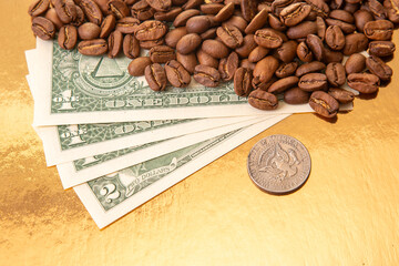U.S. dollar bills are partially covered by roasted coffee beans on a golden background,...