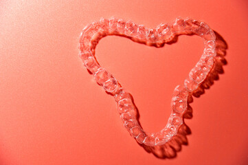 Close up of invisible aligners on pink background with copy space. Plastic braces dental retainers...
