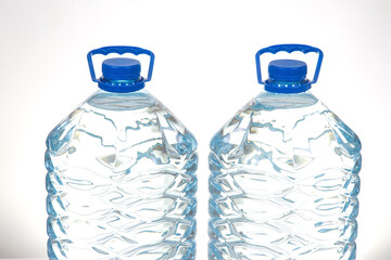 Two transparent water bottles with blue caps and a textured pattern, placed on a white surface....