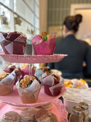 Close-up of colorful muffins and assorted baked goods arranged on a pink plate. Soft focus reveals...