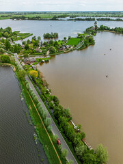 Aerial view of a scenic lakeside village with narrow peninsulas, green fields, and houses...