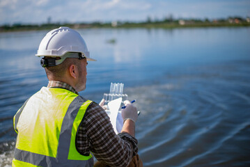 An environmental expert is examining the aquatic life in a treatment pond.