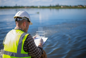 An environmental expert is examining the aquatic life in a treatment pond.