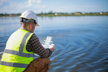 A specialist engineer at a treatment pond is checking the water quality of the treated pond.