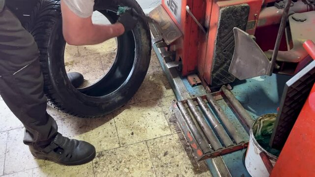 Mechanic installing car wheel on balancing machine in workshop , equipment during tire service in auto repair garage