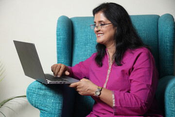 Indian woman freelancer working on laptop at home. Beautiful young woman in casual clothing using...