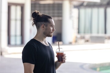 A handsome man in good body shape feels thirsty after fitness exercise. Young trainer is taking...