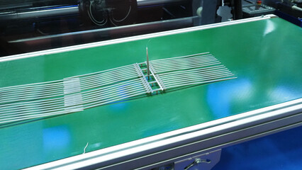 Plastic cable ties produced from an injection molding machine  and placed on a conveyor belt.