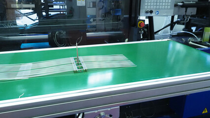 Plastic cable ties produced from an injection molding machine  and placed on a conveyor belt.