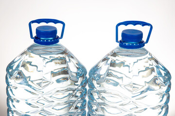Two plastic water bottles with blue lids and a unique wavy design, isolated on a white background....