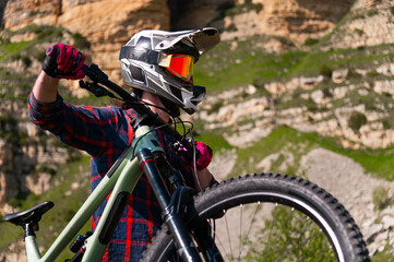 Male athlete cyclist in helmet and protective mask outdoors. MTB rider in mountainous terrain...