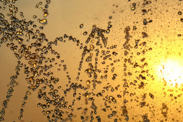 silhouettes of drops falling water fountain against the backdrop of the setting sun