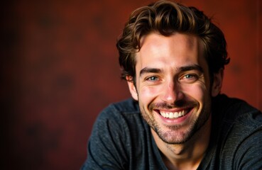 Fototapeta premium Smiling young man with wavy brown hair and blue eyes against a warm background