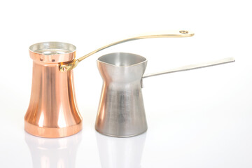 Two traditional coffee pots, one copper with a brass handle and another stainless steel with a...