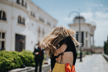 A youthful woman with flowing hair wearing vibrant clothing enjoys an outdoor city environment.
