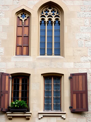 Fototapeta premium Tall, narrow windows with stone mullions and wooden shutters, window boxes, wrought iron grilles, medieval windows