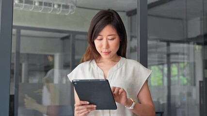 Smiling ceo entrepreneur businesswoman leader using touchscreen pc device in office. Asian middle-aged woman using tablet reading news browsing, doing online work, business learning or communication.  - Powered by Adobe