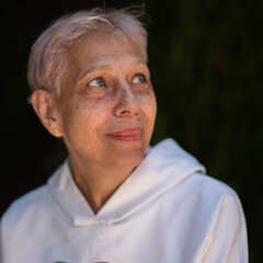 Elderly woman in white hoodie looking up with gentle smile