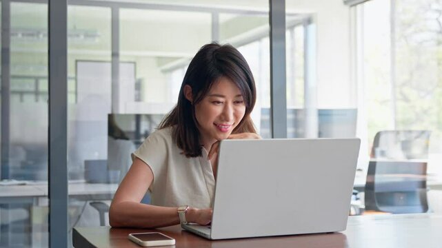30s middle-aged woman using computer technology app for banker financial work online. Mature Asian professional it specialist businesswoman working on laptop pc sitting at desk in office. Copy space