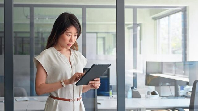 Smiling ceo entrepreneur businesswoman leader using touchscreen pc device in office. Asian middle-aged woman using tablet reading news browsing, doing online work, business communication. Copy space