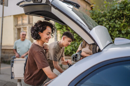 caucasian family pack luggage and hiking gear into car trunk