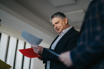 A professional businessman attentively reads papers during a formal business meeting, conveying...