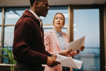 Two professionals engaged in a discussion while reviewing documents, showcasing collaboration and...