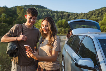young man and woman on a break from the road use mobile phone