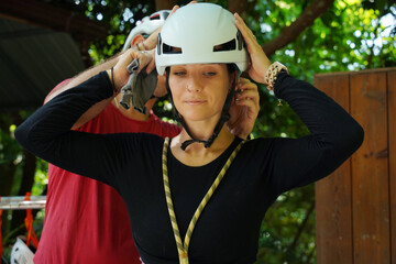 A man is assisting a woman for safety purposes before engaging ride on a zip line