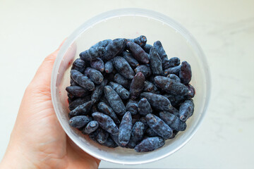 These freshly picked honeysuckle berries are displayed in a clear bowl, showcasing their deep...