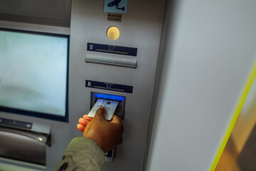 Person withdrawing cash from an automated teller machine, using a credit card for quick and easy access to funds, highlighting the convenience of modern banking and financial services