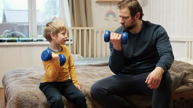 Caucasian bearded strong father with one child boy doing push ups on floor in living room. Family fitness gym at home. Sporty dad and son piggy back having fun exercise. Funny sport with kid. 4k video
