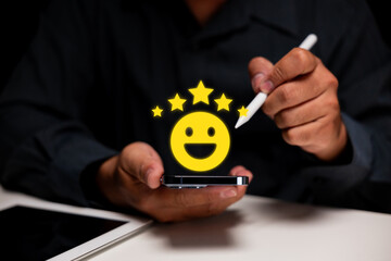A person uses a stylus on a smartphone, with a floating yellow happy face emoji surrounded by stars...