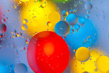 Abstract close-up of multicolored water drops on a glossy surface, blending red, yellow, blue, and...