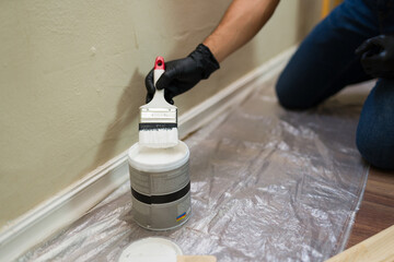 Closeup of man dipping brush in white paint can for home renovation