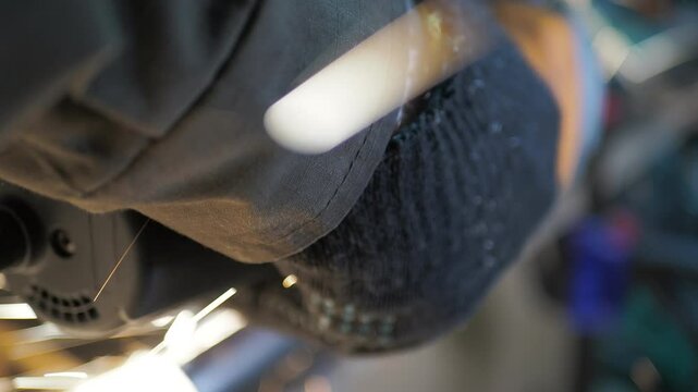 Workshop. A worker uses a angle grinder to cut a steel pipe. Close-up.
